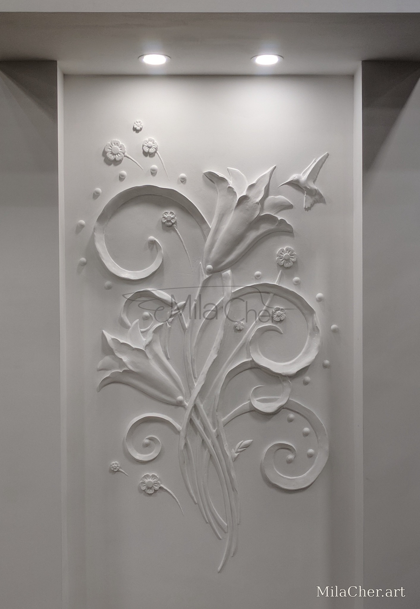 White floral sculptural wall relief with curling stems and a bird, installed in an architectural niche