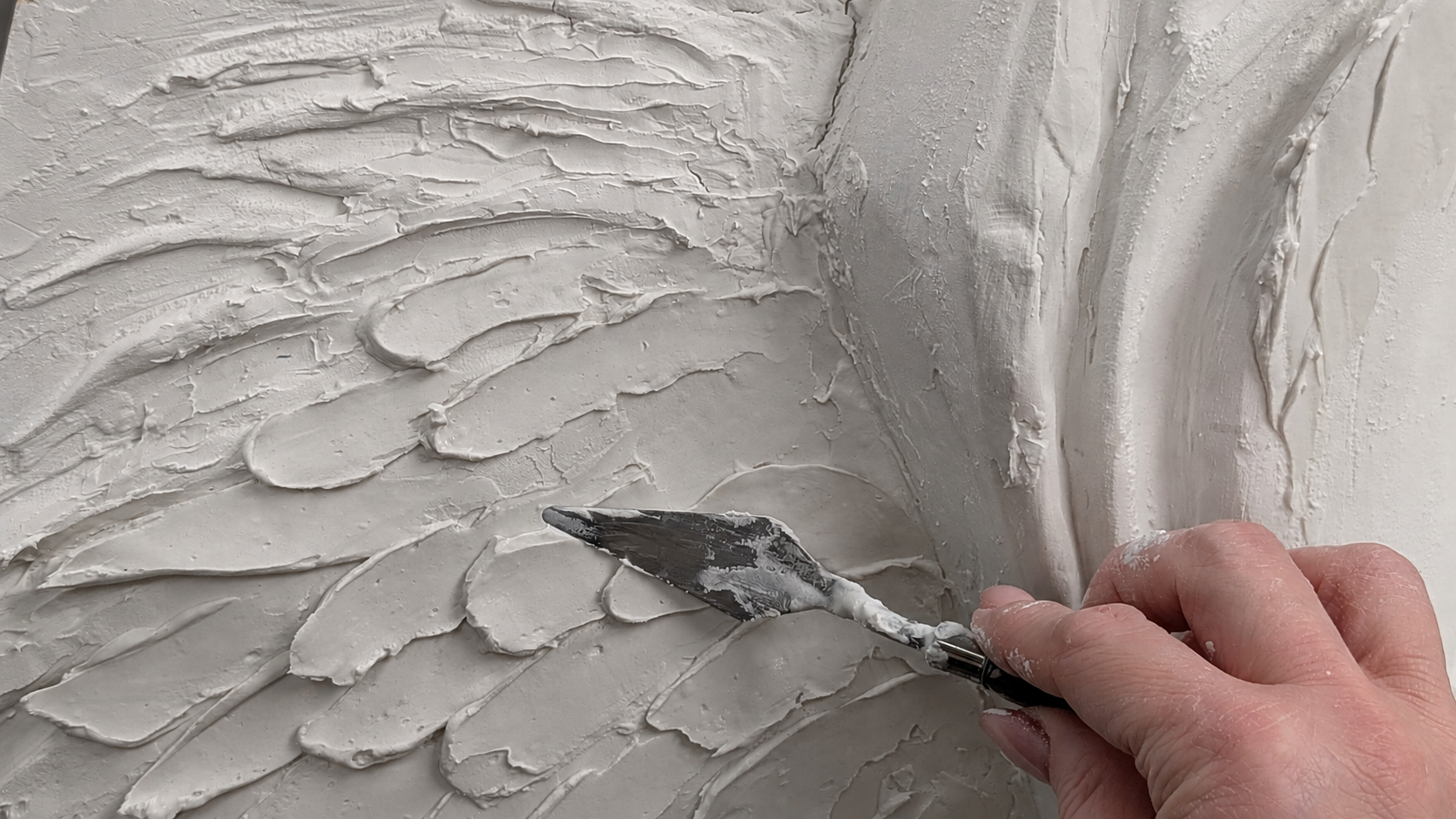Artist shaping a sculptural feather surface by hand